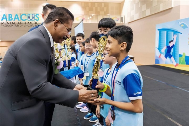 A smiling CMA student receiving a trophy on stage