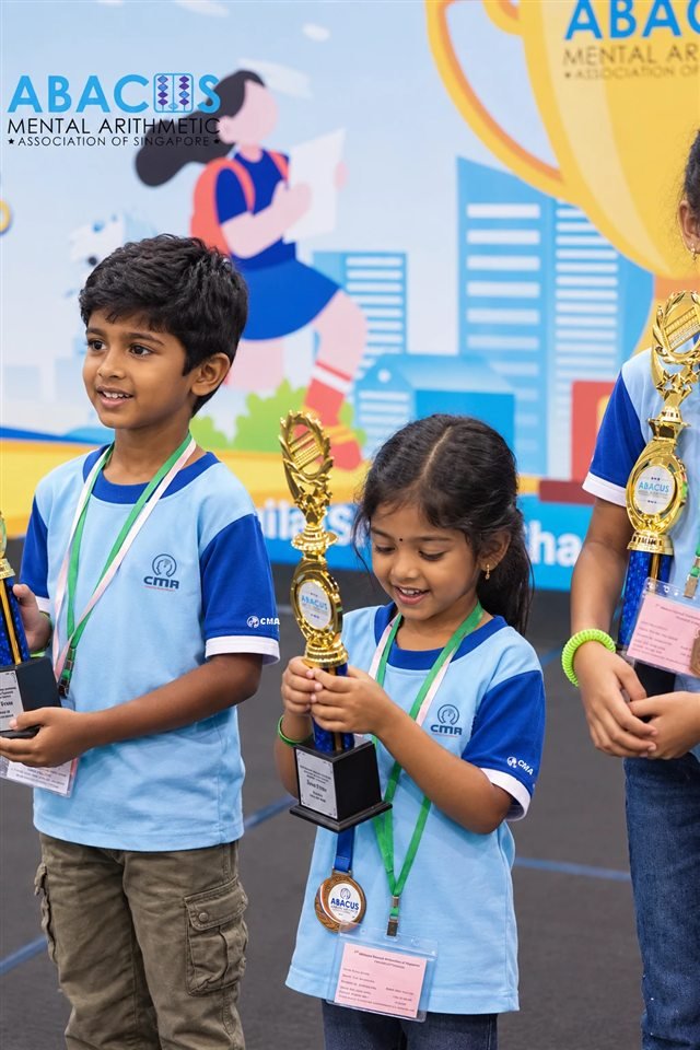 Two young CMA students smiling with their trophies on stage